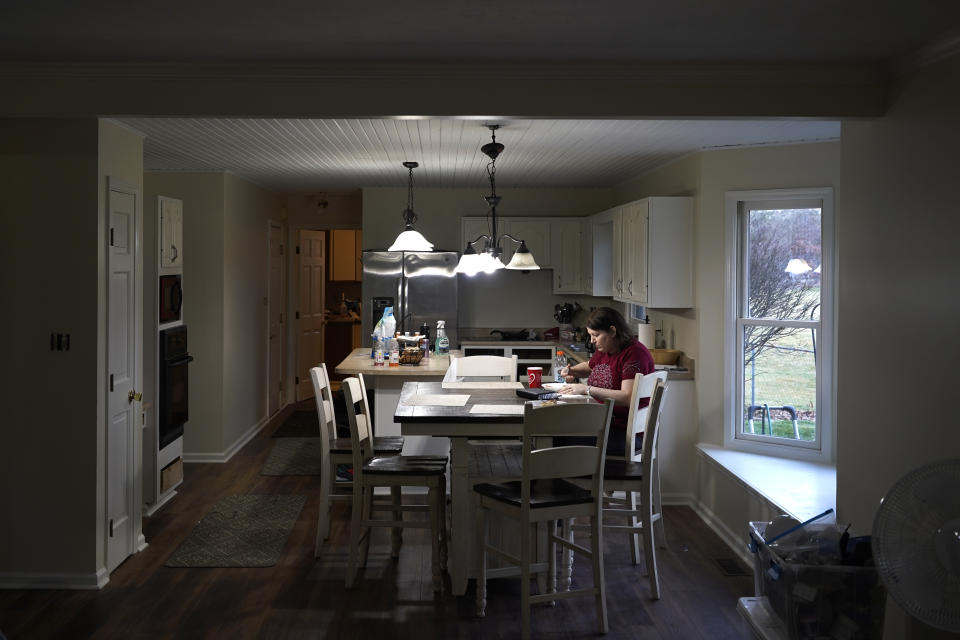 Kari Wegg sits alone eating breakfast after husband Rodney, and her two sons, Gavin and Gunnar, have left for work and school in their home in Westfield, Ind., on Tuesday, March 23, 2021. (AP Photo/Charles Rex Arbogast)