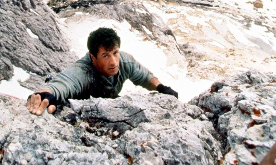 Sylvester Stallone hanging from a rock
