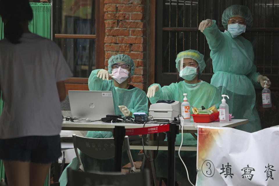 FILE - In this May 18, 2021, file photo, medical personnel wearing protective gear, guide people at a rapid coronavirus testing center after the infection alert rose to level 3 in Taipei, Taiwan. After a year of success, Taiwan is struggling with its largest outbreak since the pandemic began. When locally transmitted cases started being found in May 2021, it soon became clear that the central government was ill prepared not only to contain them, but to even detect them on a large scale due to a lack of investment in and a bias against rapid testing. (AP Photo/Chiang Ying-ying, File)