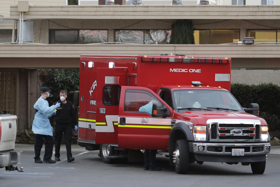 Kirkland Fire and Rescue ambulance workers walk near thier ambulance after a patient was loaded for transport, Tuesday, March 10, 2020, at the Life Care Center in Kirkland, Wash., near Seattle. The nursing home is at the center of the outbreak of the new coronavirus in Washington state. (AP Photo/Ted S. Warren)