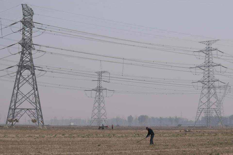 FILE - A farmer tills his land under power lines near central China's Henan province on Oct. 23, 2021. Up to 2.3 billion people around the world are still using polluting fuels to cook and 675 million don't have electricity, according to a report released Tuesday, June 6, 2023 by five international organizations. (AP Photo/Ng Han Guan, File)