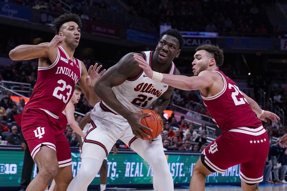 Illinois center Kofi Cockburn (21) looks to shoot between Indiana forwards Trayce Jackson-Davis (23) and Race Thompson (25) in the first half of an NCAA college basketball game at the Big Ten Conference tournament in Indianapolis, Friday, March 11, 2022. (AP Photo/Michael Conroy)