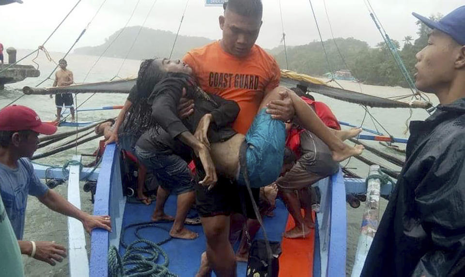 In this photo provided by the Philippine Coast Guard, coast guard rescuers carry a victim alive after being plucked from the waters off Guimaras Sunday, Aug. 4, 2019 in Iloilo province in central Philippines. Philippine police say rescuers have plucked more bodies in rough seas where three ferry boats capsized after being buffeted by fierce wind and waves off two central provinces.(Philippine Coast Guard Photo Via AP)