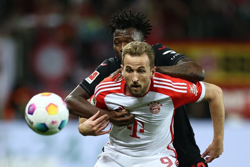 Bayern Munich's Harry Kane and Leverkusen's Edmond Tapsoba (L) battle for the ball during the German Bundesliga soccer match between Bayer Leverkusen and Bayern Munich at BayArena. Rolf Vennenbernd/dpa