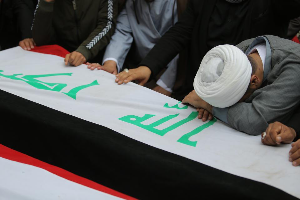 Mourners and militia fighters mourn by the flag-draped coffins of two fighters of the Popular Mobilization Forces who were killed during the US attack on against militants in Iraq, during their funeral procession at the Imam Ali shrine in Najaf, Iraq, Saturday, March 14, 2020. The U.S. launched airstrikes on Thursday in Iraq, targeting the Iranian-backed Shiite militia members believed responsible for a rocket attack that killed and wounded American and British troops at a base north of Baghdad. (AP Photo/Anmar Khalil)