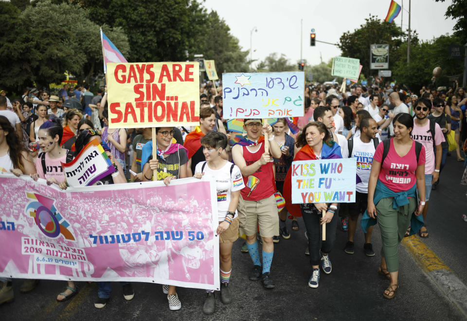 Participants hold signs during the annual Gay Pride parade in Jerusalem, Thursday, June 6, 2019. Thousands of people are marching through the streets of Jerusalem in the city's annual gay pride parade, a festival that exposes deep divisions between Israel's secular and Jewish ultra-Orthodox camps. (AP Photo/Ariel Schalit)