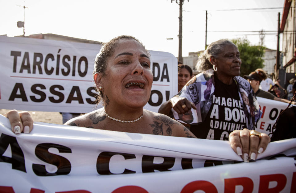 A woman joins a protest against a police raid that killed more than a dozen of people in Guaruja, Sao Paulo state, Brazil, Wednesday, Aug. 2, 2023. The death toll from the raid has climbed to at least 14, in a sprawling operation that has raised questions about the use of lethal force by police. (AP Photo/Tuane Fernandes)