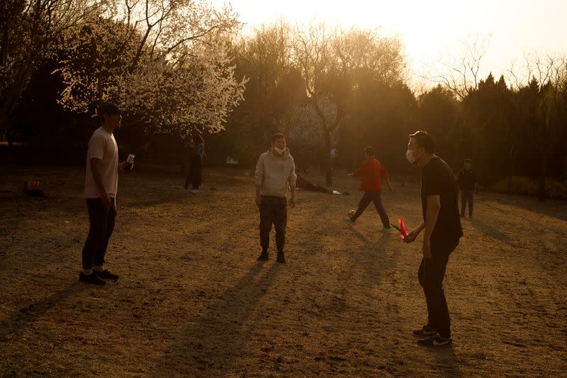 People wearing protective masks play in a park on a sunny day in Beijing as the country is hit by an outbreak of the novel coronavirus disease (COVID-19)