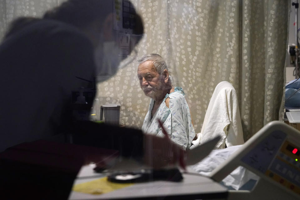 Jesus Aguirre Medina, a Covid-19 patient with a nutritionist looking over paperwork in his room in the acute care unit of Harborview Medical Center, on Friday. (Elaine Thompson / AP)