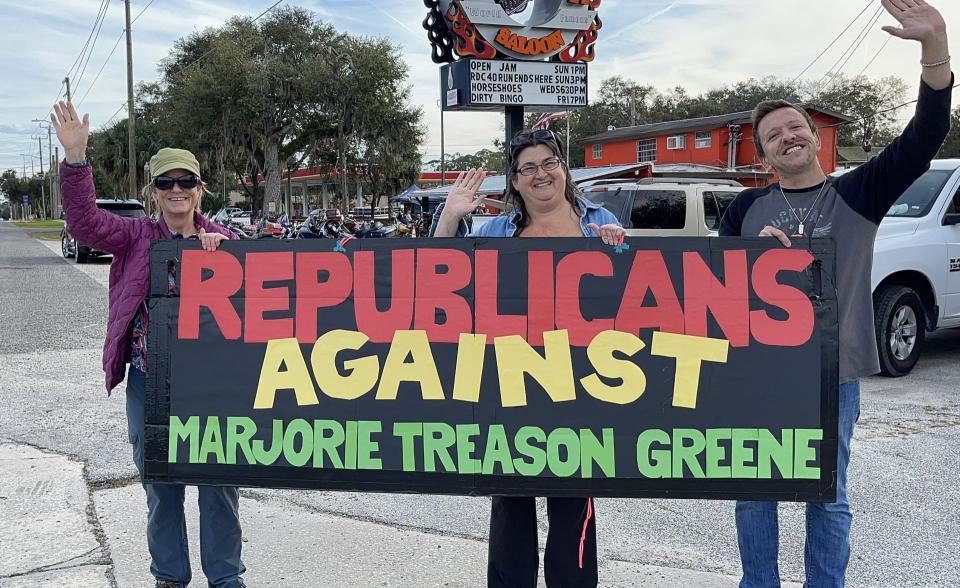 A small group of protestors from Daytona Beach, Sebastian and Spokane, Washington, display a sign outside the Iron Horse Saloon Sunday where Congresswoman Marjorie Taylor Greene signed books for fans and spoke about the Jan. 6 U.S. Capitol riots and other issues.