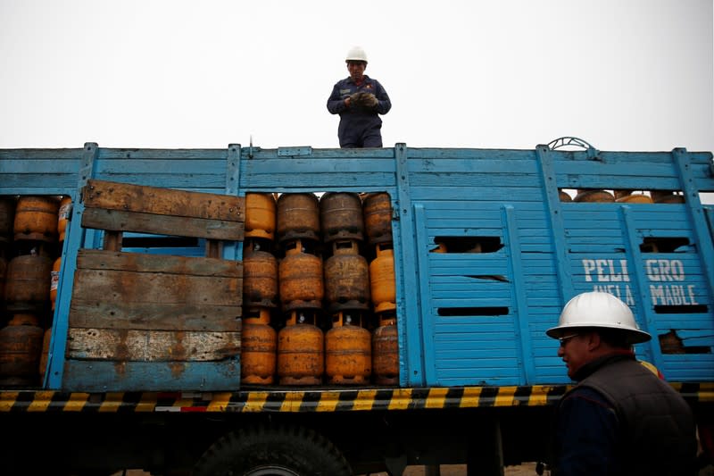 Workers stand next to gas cylinders near petrol plant of Senkata, that normalizes fuel distribution in El Alto outskirts of La Paz