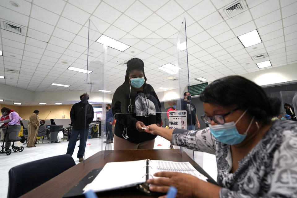 FILE - A woman presents her identification to vote through a plexiglass barrier, to prevent the spread of the coronavirus, on election day at the Matin Luther King, Jr. Elementary School, in the Lower Ninth Ward of New Orleans on Nov. 3, 2020. Louisiana’s secretary of state and attorney general asked the U.S. Supreme Court on Friday, June 17, 2022, to put a hold on a federal judge’s order for the state to create a second majority Black congressional district by Monday. (AP Photo/Gerald Herbert, File)