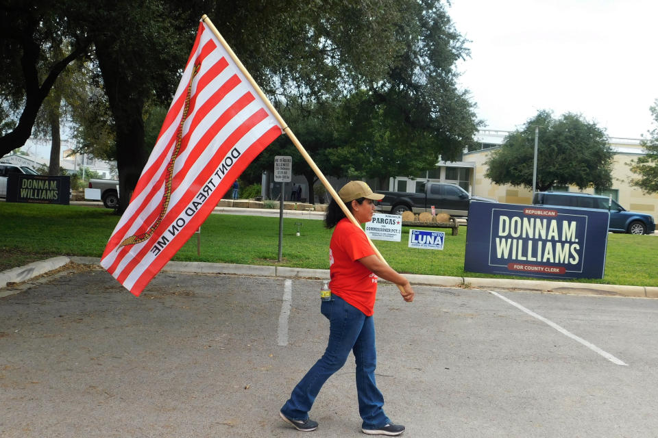 Dolly Schultz sostiene una bandera afuera de una casilla electoral en el primer día de votación anticipada, el lunes 24 de octubre de 2022, en Uvalde, Texas. (AP Foto/Acacia Coronado)