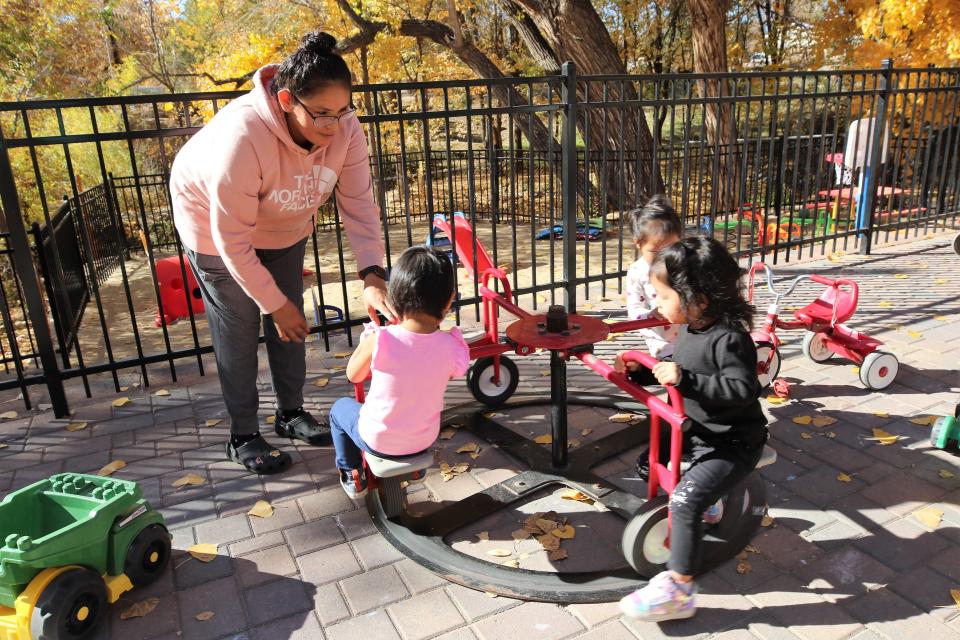 A Gold Star Academy & Child Development Center employee Adrianne Lopez, left, pushes children on merry-go-round in the infant-toddler playground at the center on Nov. 5 at 1115 N. Auburn Ave. in Farmington,