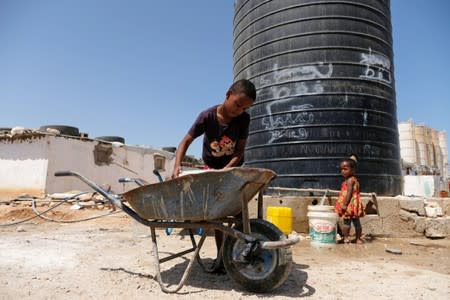 Libyan children displaced from the town of Tawergha fill containers with water at a displaced camp in Benghazi