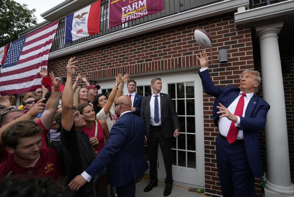 Former President Donald Trump throws a football to the crowd during a visit to the Alpha Gamma Rho, agricultural fraternity, at Iowa State University before an NCAA college football game between Iowa State and Iowa, Saturday, Sept. 9, 2023, in Ames, Iowa. (AP Photo/Charlie Neibergall)