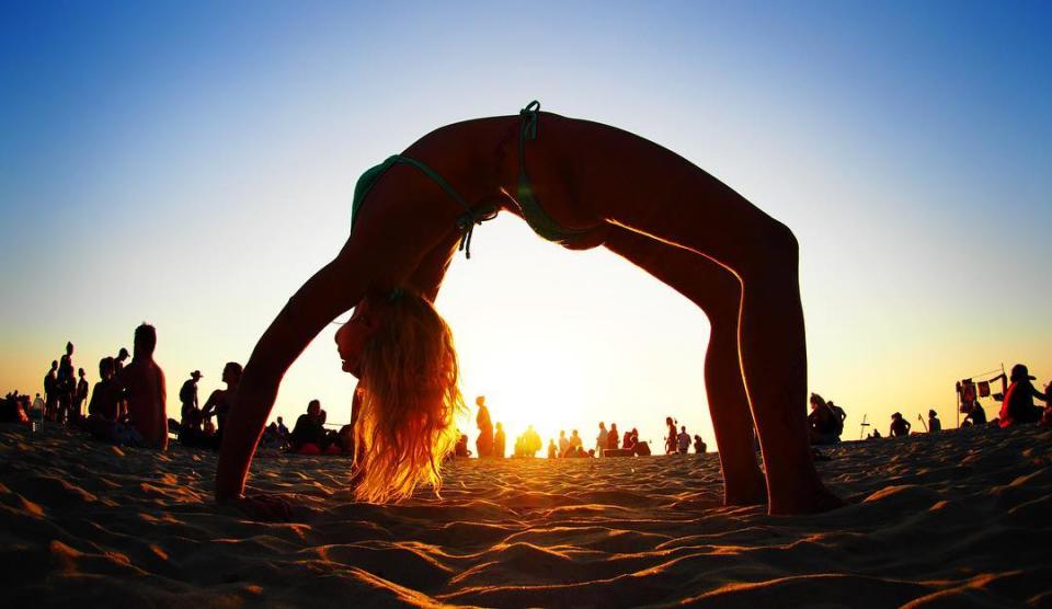 Olympus 9mm body cap image of a woman performing a yoga pose on the beach at sunset