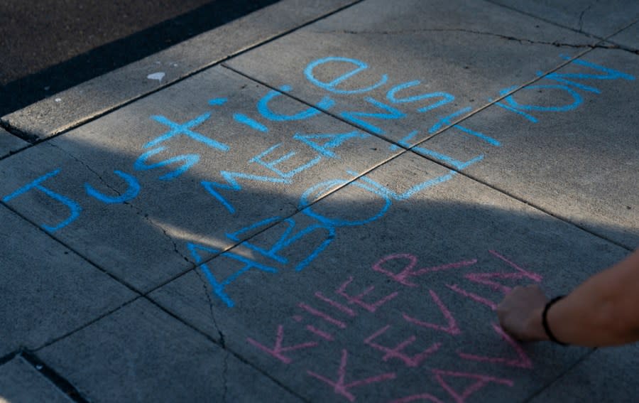 A protester writes a message in favor of police abolition with sidewalk chalk as people rally after body camera footage was released of a Seattle police officer joking about the death of Jaahnavi Kandula, a 23-year-old woman hit and killed in January by officer Kevin Dave in a police cruiser, Thursday, Sept. 14, 2023, in Seattle. (AP Photo/Lindsey Wasson)