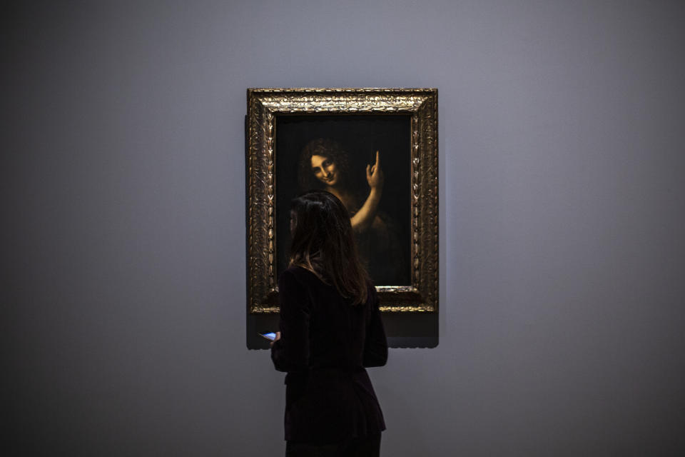 A journalist studies Saint Jean Baptiste artwork by Leonardo da Vinci during a visit at the Louvre museum Sunday, Oct. 20, 2019 in Paris. A unique group of artworks is displayed at the Louvre museum in addition to its collection of paintings and drawings by the Italian master. The exhibition opens to the public on Oct. 24, 2019. (AP Photo/Rafael Yaghobzadeh)