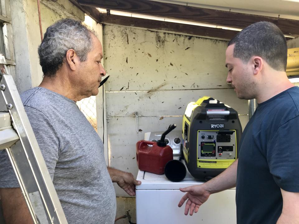 Jesse Vazquez, left, and his son debate where to keep the generator outside their house in Bayamon, Puerto Rico. (Photo: Caitlin Dickson/Yahoo News)