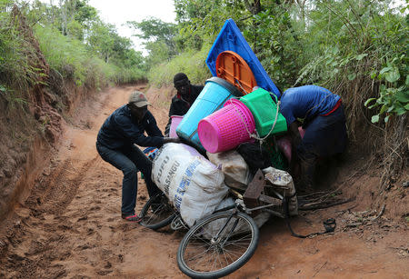 Congolese migrants expelled from Angola attempt to push a rented bicycle to transport their belongings along the dirt road to Tshikapa, Kasai province near the border with Angola in the Democratic Republic of the Congo, October 12, 2018. REUTERS/Giulia Paravicini