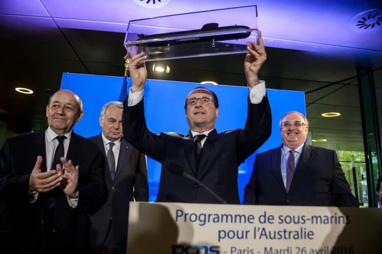 French President Francois Hollande (C) receives a model submarine from French naval defence contractor DCNS chief executive officer Herve Guillou (R), during a visit to the DCNS headquarters in Paris, in April 2016