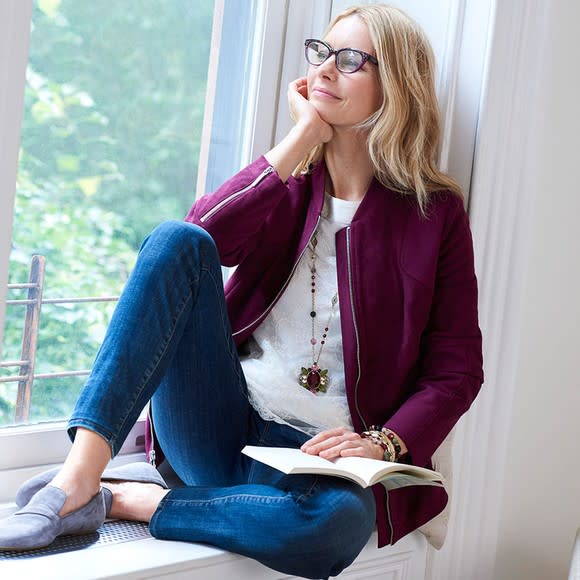 A woman holding a book open and resting her chin on her hand