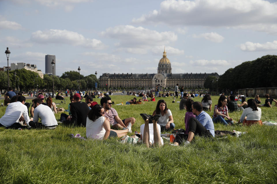 Parisinos se relajan en la grama del Palacio de los Inválidos, el domingo 24 de mayo de 2020. (AP Foto/Francois Mori)