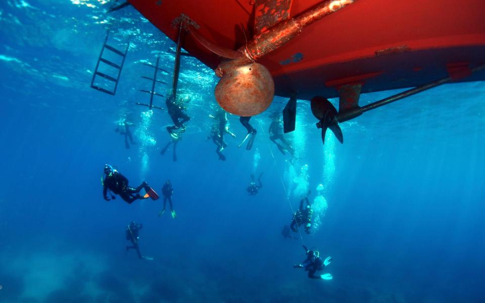 group of divers under red boat - Dive Worldwide Malta