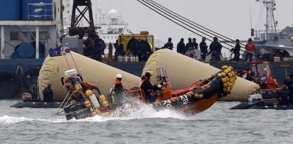 Searchers and divers look for people believed to have been trapped in the sunken ferry boat Sewol near the buoys which were installed to mark the vessel in the water off the southern coast near Jindo, south of Seoul, South Korea, Tuesday, April 22, 2014. One by one, coast guard officers carried the newly arrived bodies covered in white sheets from a boat to a tent on the dock of this island, the first step in identifying a sharply rising number of corpses from a South Korean ferry that sank nearly a week ago. (AP Photo/Lee Jin-man)