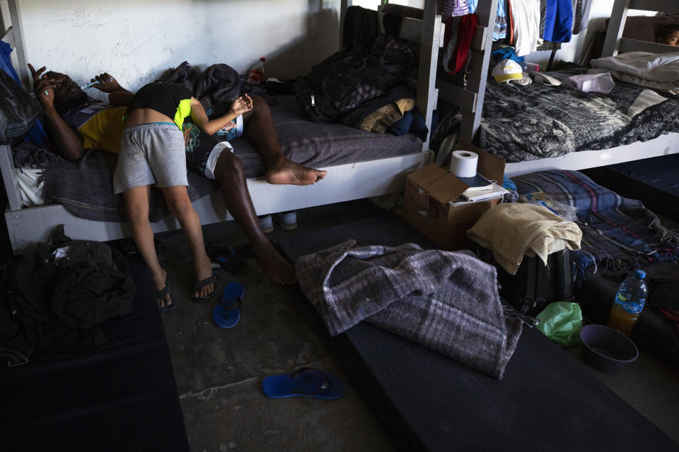 In this July 25, 2019, photo, a boy from Honduras jokes with an African man in the dormitory at El Buen Pastor shelter for migrants in Cuidad Juarez, Mexico. (AP Photo/Gregory Bull)