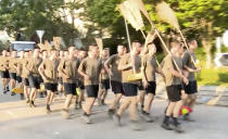 In this image made from video, People’s Liberation Army soldiers, with brooms, arrive to clean up the protest area at Hong Kong Baptist University in Hong Kong, Saturday, Nov. 16, 2019. Troops from the Chinese army joined an effort to clean up debris outside the university, which was the site of clashes this week. (Television Broadcasts Limited Hong Kong via AP)
