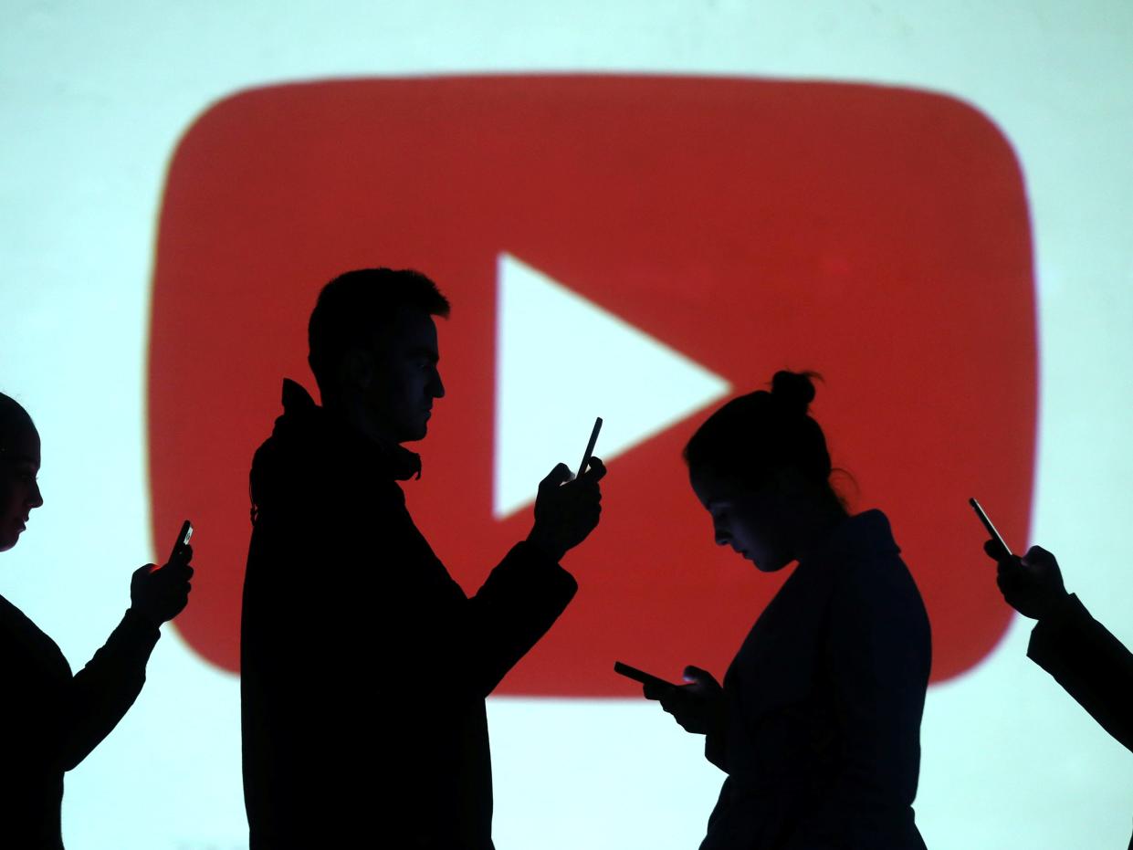 FILE PHOTO: Silhouettes of mobile users are seen next to a screen projection of Youtube logo in this picture illustration taken March 28, 2018.  REUTERS/Dado Ruvic/Illustration