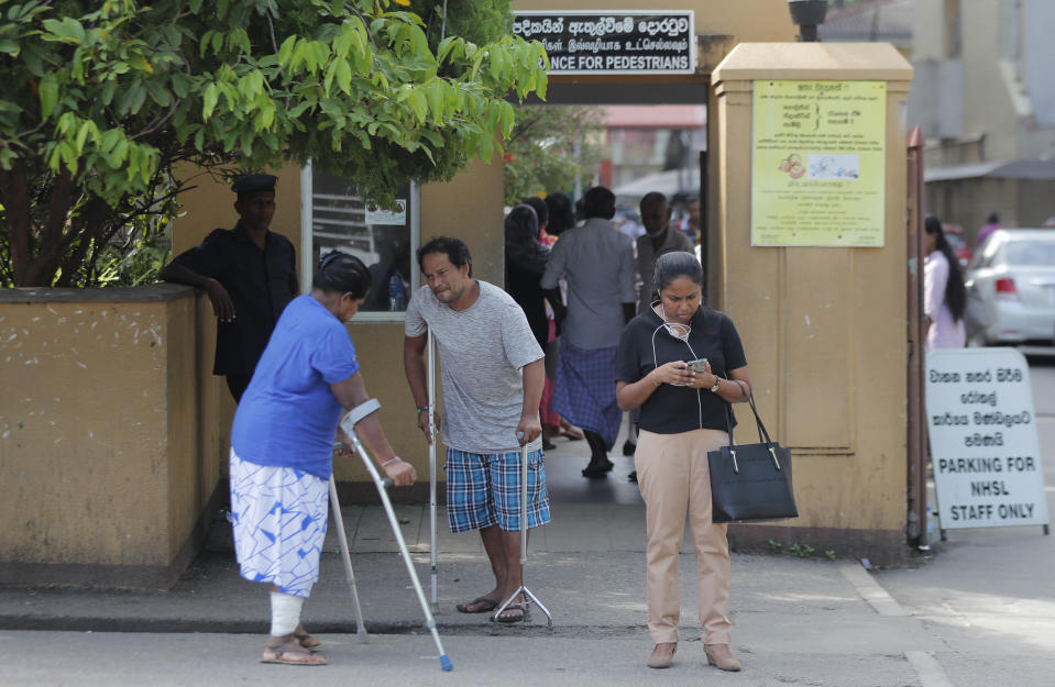 Sri Lankan patients and others wait outside the National Hospital during a day long token strike launched by the members of Government Medical Officers Association in Colombo, Sri Lanka, Wednesday, Sept. 18, 2019. The trade union action is to demand the government resolve salary anomalies faced by the doctors serving at state-run hospitals. (AP Photo/Eranga Jayawardena)