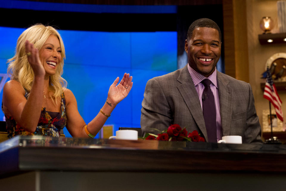 Former football player Michael Strahan, right, sits with Kelly Ripa on the set of the newly named "Live! with Kelly and Michael" on Tuesday, Sept. 4, 2012 in New York. Strahan joined the popular morning show as a permanent co-host on Tuesday, fulfilling a joking prophecy he made to Regis Philbin more than four years ago. The gap-toothed former New York Giant jogged onto the morning show set and picked up co-host Kelly Ripa in a bear hug, lifting her off her feet. He replaces Philbin, who left last November. Strahan was the survivor in a series of on-air tryouts of potential co-hosts since Philbin left, and his hiring has been an open secret for the past two weeks. (Photo by Charles Sykes/Invision/AP Images)
