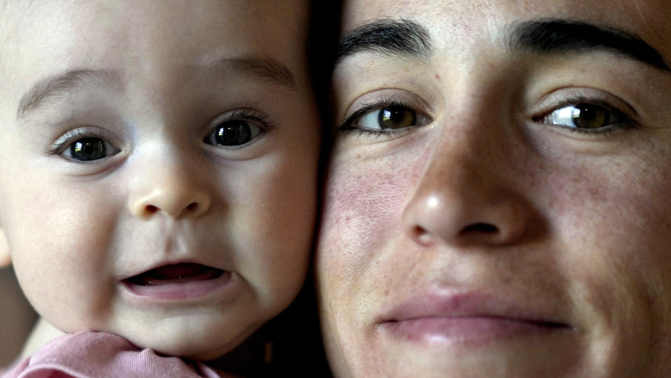 Belén Casetta sostiene a su hija Lina en su residencia en Pilar, Argentina, el lunes 9 de octubre de 2023. Casetta competirá en los 3.000 metros de los Juegos Panamericanos en Chile. (AP Foto/Natacha Pisarenko)