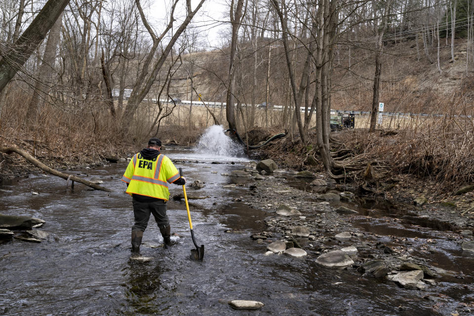 Ron Fodo, in yellow EPA jacket, wades through the creek.