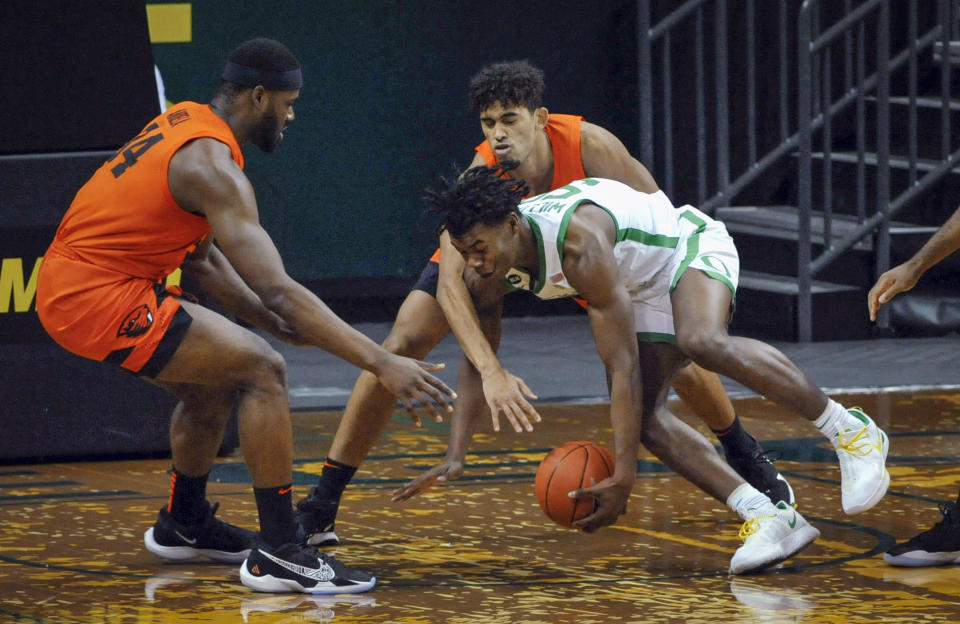 Oregon State forward Rodrigue Andela, left, and Julien Franklin defend against Oregon forward Eric Williams Jr. during the first half of an NCAA college basketball game Saturday, Jan. 23, 2021, in Eugene, Ore. (AP Photo/Andy Nelson)