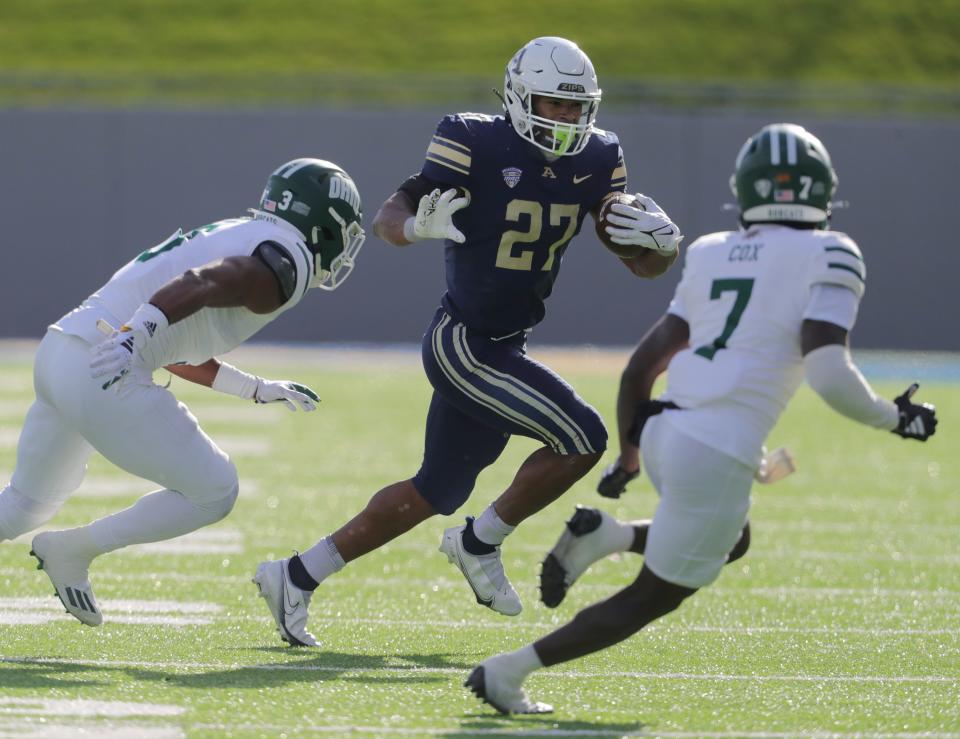 University of Akron running back Lorenzo Lingard looks for yardage as Ohio defenders Jeremiah Wood, left, and Torrie Cox Jr. pursue on Friday, Nov. 24, 2023.