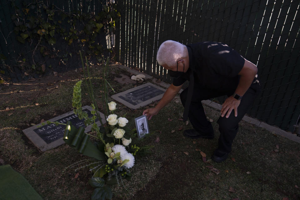 Clyde Matsumura places of a photo of his grandfather, Giichi Matsumura, next to his gravestone after a memorial service at Woodlawn Cemetery in Santa Monica, Calif., Monday, Dec. 21, 2020. Giichi Matsumura, who died in the Sierra Nevada on a fishing trip while he was at the Japanese internment camp at Manzanar, was reburied in the same plot with his wife 75 years later after his remains were unearthed from a mountainside grave. (AP Photo/Jae C. Hong)