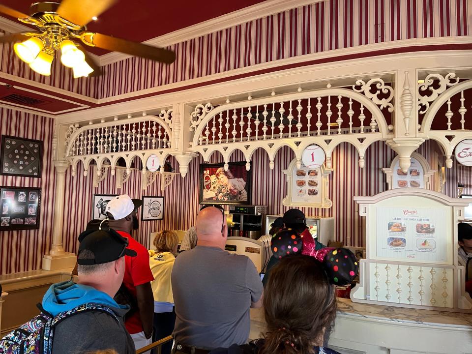 people standing in a line to order food inside casey's corner at magic kingdom