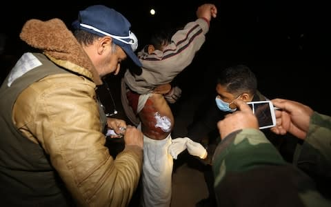 Medical personnel give aid to a migrant upon arrival at a naval base in Tripoli late on January 31, 2018, after migrants were rescued off Libya's coast when their boat sunk. - Credit: AFP