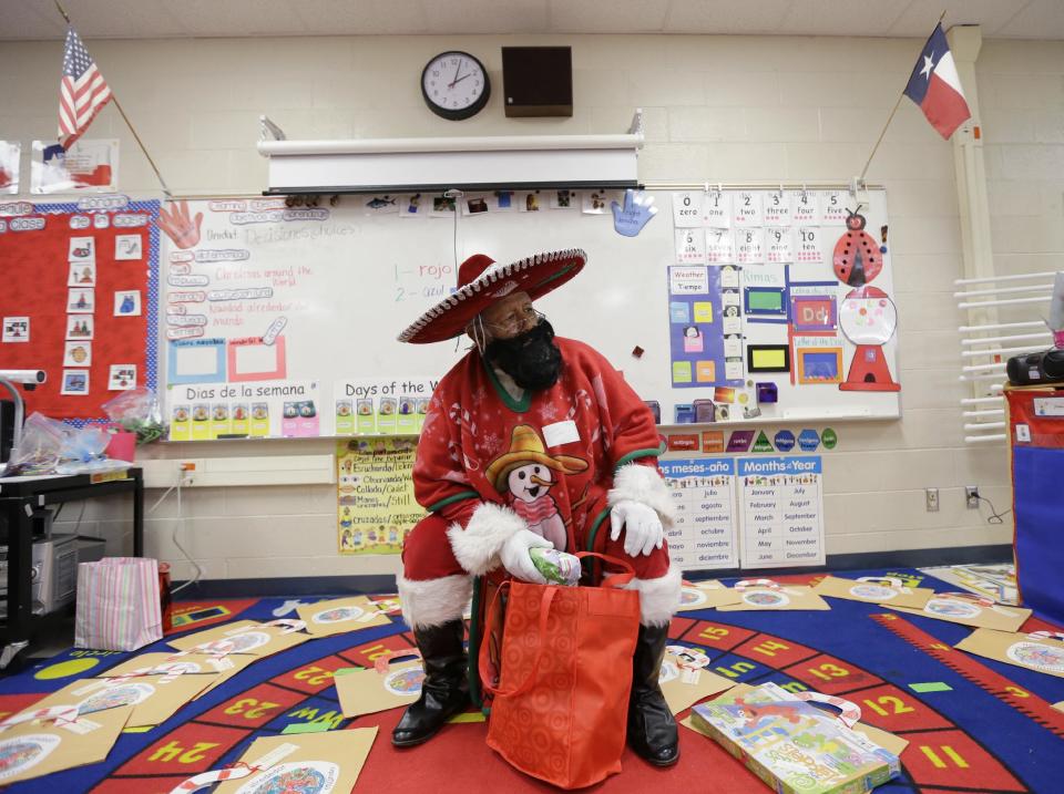In this Friday, Dec. 20, 2013, photo, Pancho Claus, Rudy Martinez, prepares to hands out gifts in a class during a visit to Knowlton Elementary School, in San Antonio. Pancho Claus, a Tex-Mex Santa borne from the Chicano civil rights movement in the late 1970s and early 1980s, is now an adored Christmas fixture in many Texas cities. (AP Photo/Eric Gay)