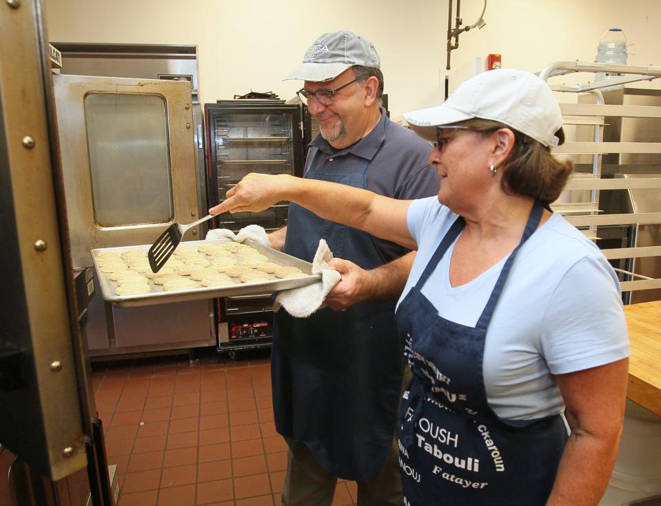 Chuck Abraham, left, assists his wife, Mary Beth Abraham, pastry chairwoman, with checking the ma'mool cookies as they bake at Our Lady of the Cedars in preparation for the Lebanese Festival.