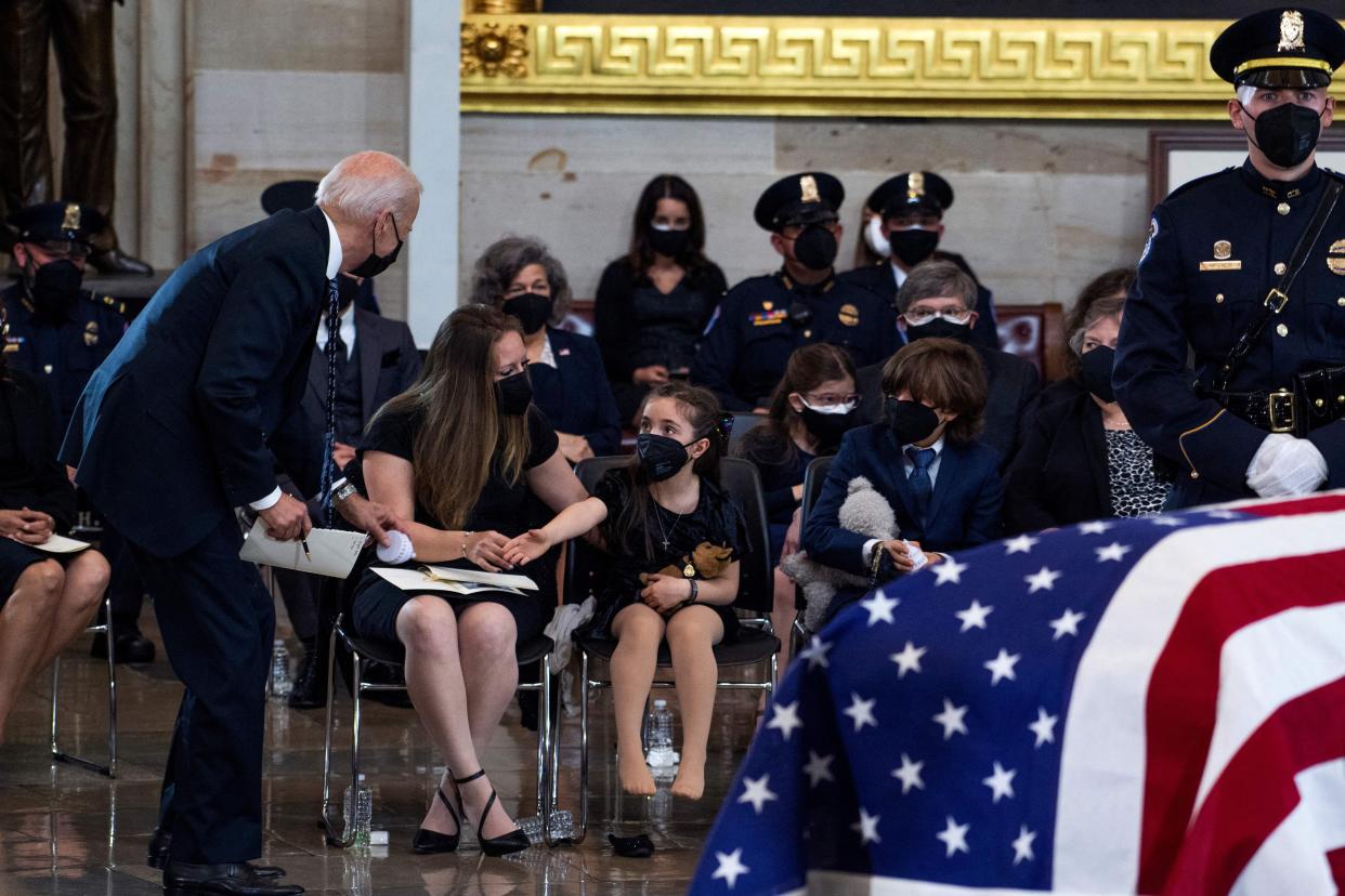 President Joe Biden picks up a toy Capitol dome for Abigail Evans, 7, the daughter of US Capitol Police Officer William "Billy" Evans, as her brother Logan, 9, and their mother Shannon Terranova, look on, while paying respects as his remains lie in honor in the Capitol Rotunda in Washington, DC, on April 13, 2021.