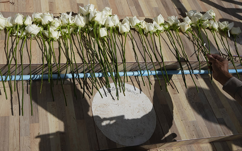 A police officer lays flowers during a ceremony for those killed in the attack on the Young Children's Development Center in Thailand