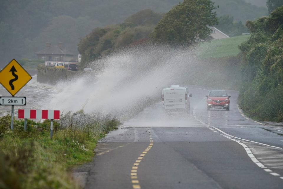 Autos passieren Wellen, die über eine Mauer auf die Straße in Youghal, Co Cork (PA) krachen.