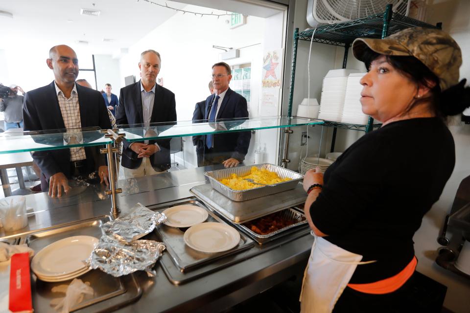 Massachusetts Veterans Services Secretary Jon Santiago, New Bedford Mayor Jon Mitchell, and Veterans Transition House Executive Director Jim Reid speak with cafeteria worker Lisa Shea during a visit to the Veterans Transition House in New Bedford.