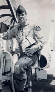 A man in a uniform next to a plane.