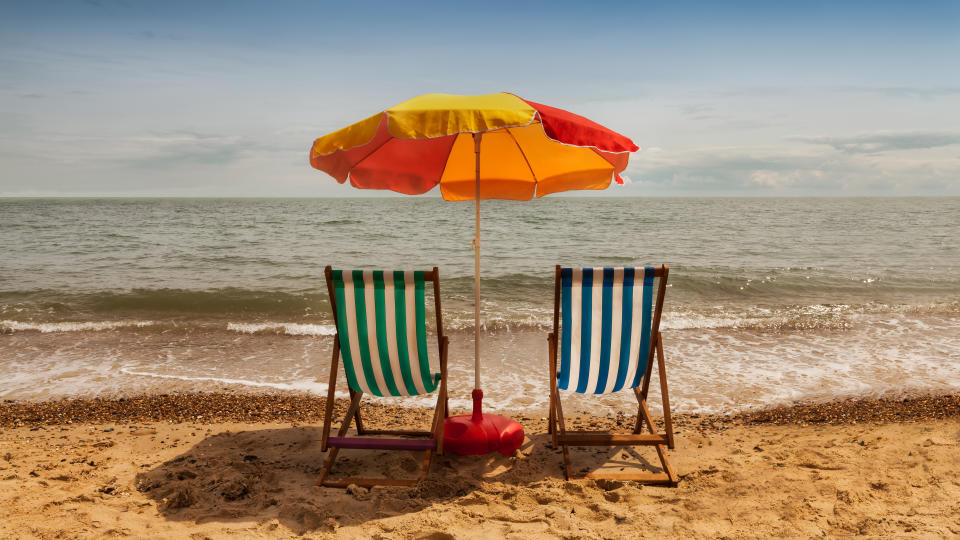 Clacton, Essex, UK. June 28, 2014.
Image shows two deck chairs and parasol on a sandy beach on a sunny summer day.